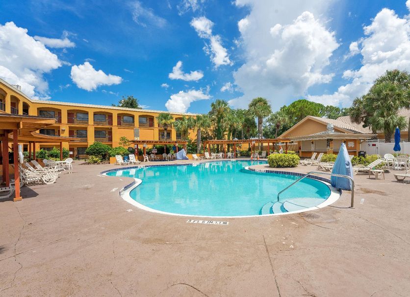 Mi Casa Hotel Orlando outdoor pool with lounge chairs and palm trees under a blue sky