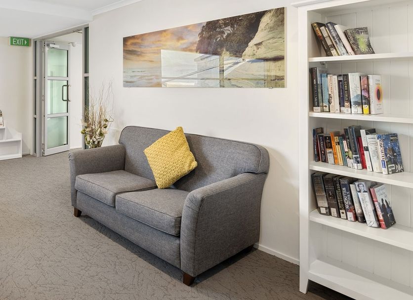 Aristotles North Shore in Auckland lounge with gray sofas, bookshelves, and window seating