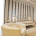 Relais La Pretura in Vieste: bright bedroom with white metal bed, armchair, wardrobe and striped accent wall