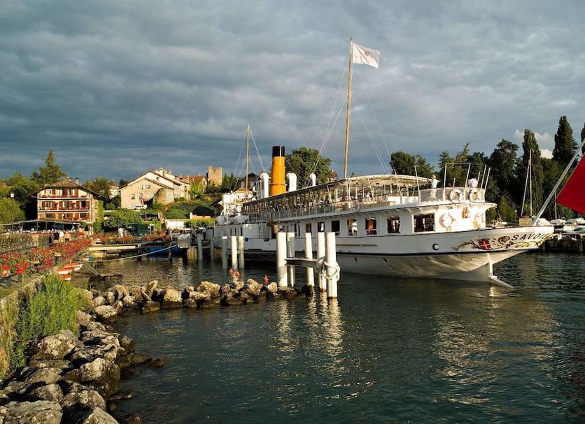 Hotel Restaurant Du Port in Yvoire with a docked white boat on the waterfront under stormy skies