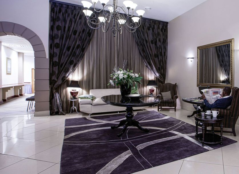 Apollo Hotel Johannesburg lobby lounge with chandelier, purple rug, sofas and floral arrangements