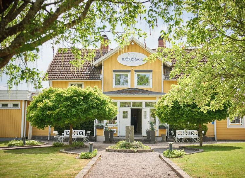 Hotell Björkhaga in Mullsjö, yellow hotel facade with entrance path and manicured garden