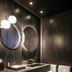 Jiva Hill Resort - Genève bathroom with double sink vanity, round mirrors and dark stone finishes in Crozet