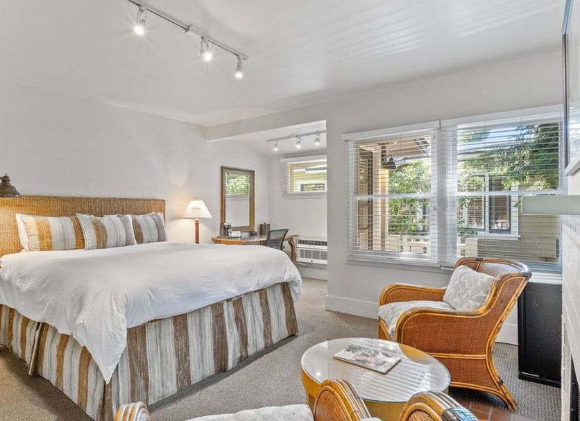 The Upham Hotel Santa Barbara guest room with king bed, wicker chair, and large windows