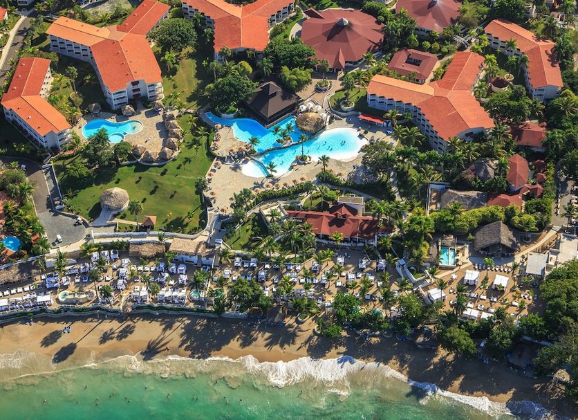 Aerial view of Lifestyle Crown Residence Suites in Puerto Plata with pools, beachfront, and red-roofed buildings