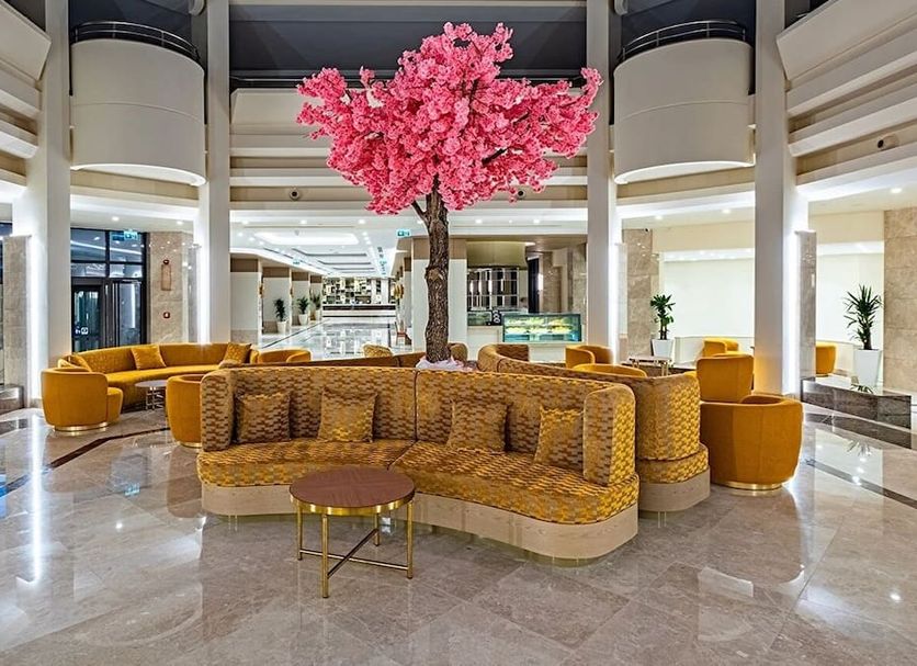 Ozkaymak Marina Hotel in Kemer lobby with curved wicker seating and a pink blossom tree centerpiece