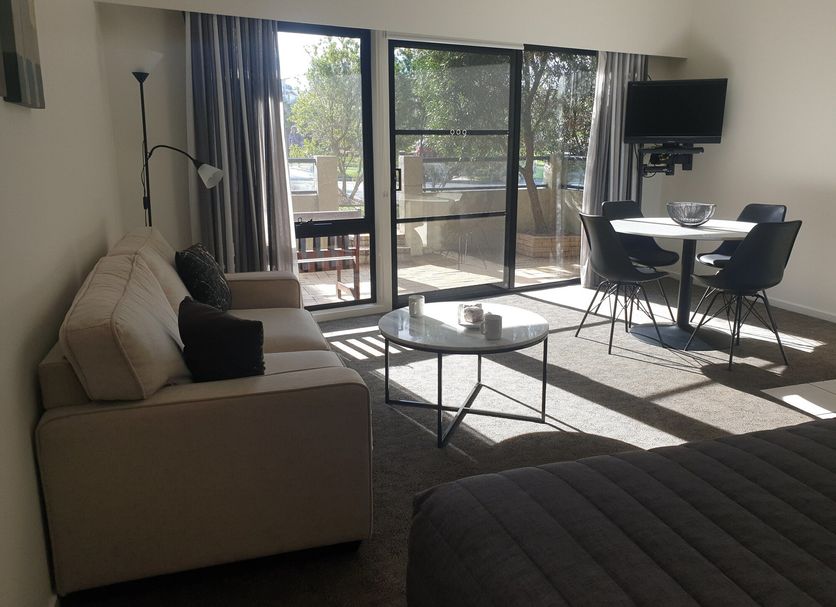 Metung Waters Motel and Apartments living room with sofa, table, TV, and sliding glass doors to patio