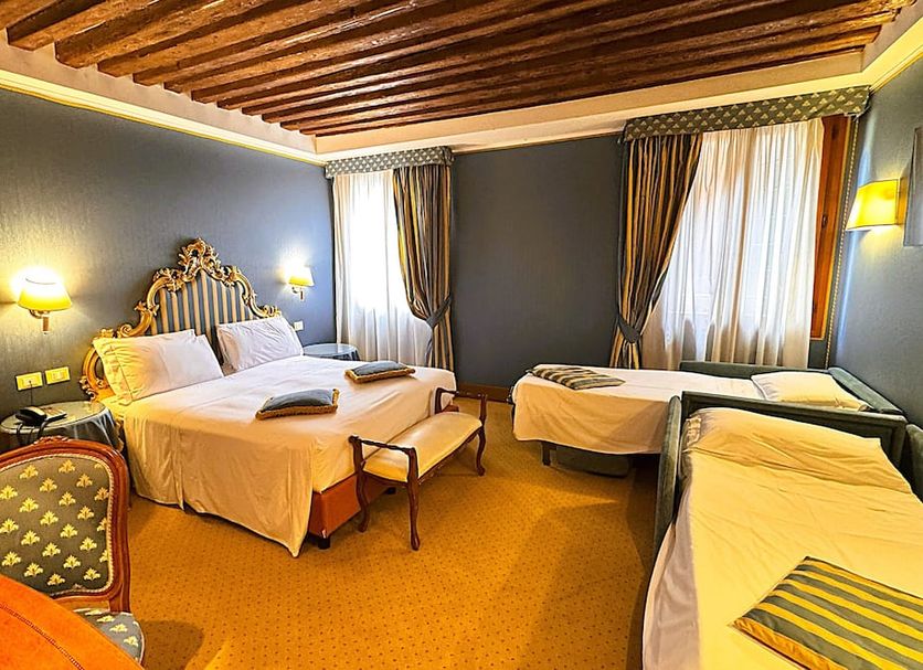 Hotel Corte Contarina in Venice guest room with three beds, wood-beamed ceiling and large windows
