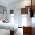 De House Hotel Sibu guest room with two twin beds, wood furnishings and patterned wall art