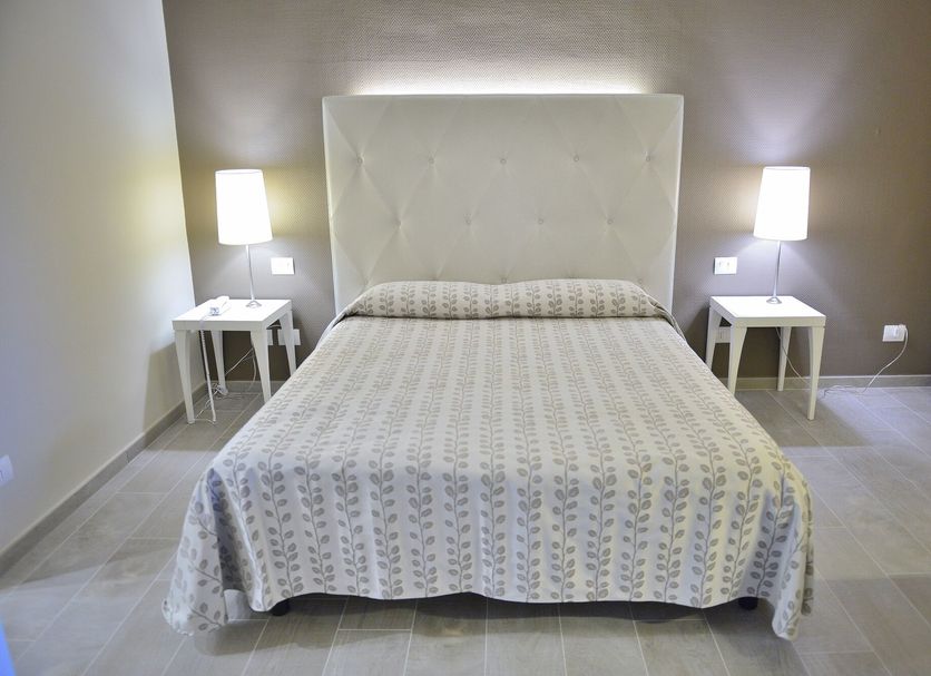 Hotel degli Ulivi in Ferrandina: a neatly made bed with tufted headboard and matching bedside lamps
