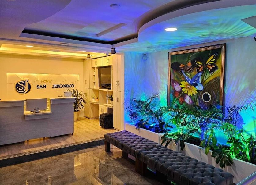 Hotel San Jeronimo Armenia lobby with front desk, tufted bench, and colorful wall art