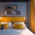ibis Styles Saint-Malo Centre Historique room with yellow headboard, twin beds, and framed wall art