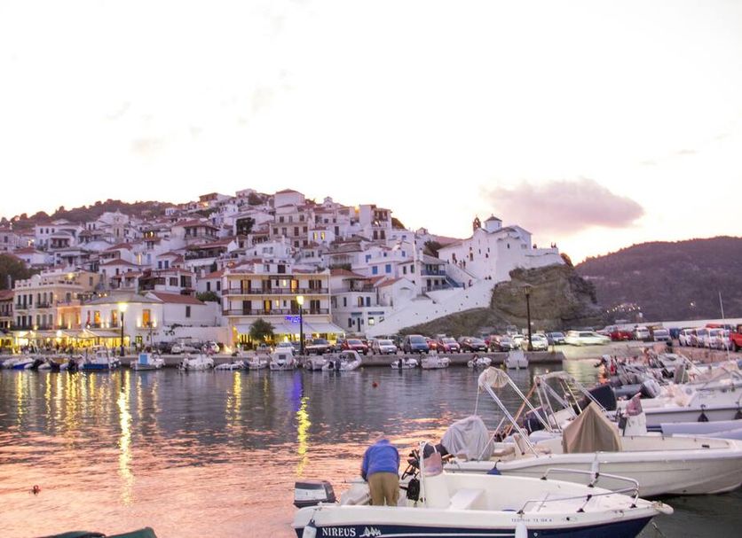 Georgios L in Skopelos overlooking the harbor with boats and hillside whitewashed buildings at sunset
