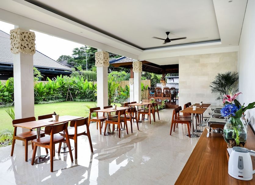 Mahana Living, Denpasar: open-air dining area with tables, chairs, and garden view