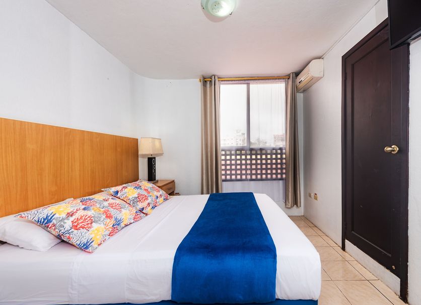 Hostal North Seymour in Puerto Ayora: simple guest room with bed, window, curtain, and air conditioner