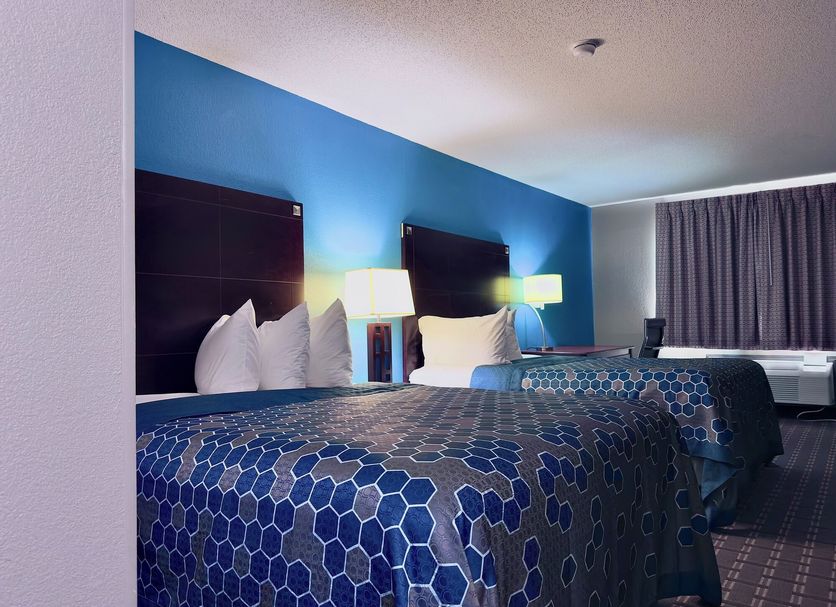 American Inn Cedar Rapids South guest room with two beds, blue accent wall, and patterned bedspreads