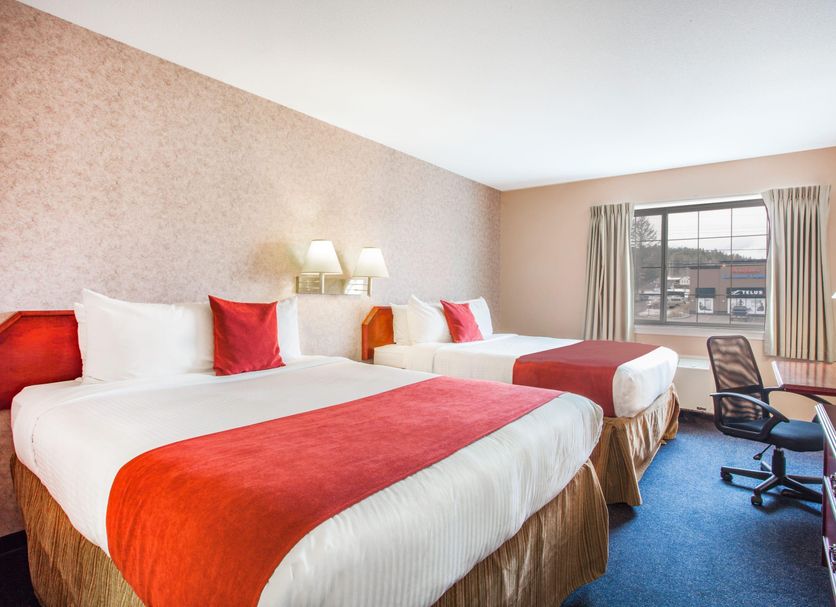 Ramada by Wyndham 100 Mile House room with two queen beds and a window view of the parking lot