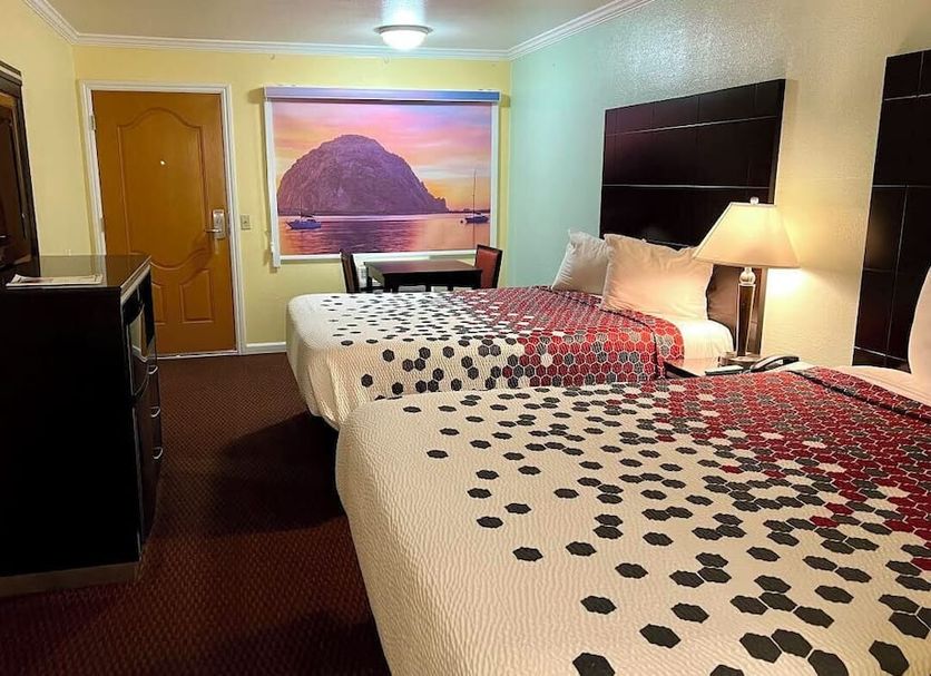 Morro Bay Beach Inn room with two beds, dresser and lamp, plus a Morro Rock wall mural in Morro Bay