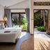 M Village Phu Quoc room with bed and sliding glass doors opening to a lush garden patio