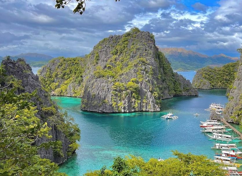 The Funny Lion, Coron: scenic lagoon with turquoise water, limestone cliffs, and docked boats