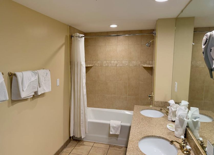 Aquarius Oceanfront Hotel in Virginia Beach bathroom with tub, tiled shower wall, and double vanity