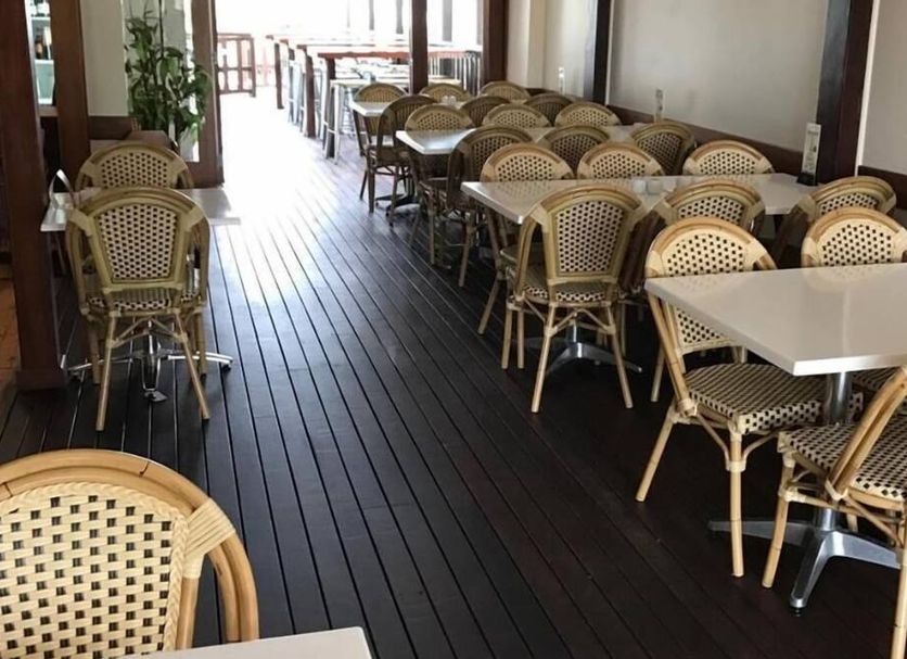 Exchange Hotel Toogoolawah dining area with woven chairs and tables on a covered wooden deck