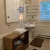 Mountain Meadows Inn & Chalet Suites bathroom with pedestal sink, mirror, shelves, and woven bench in Ashford