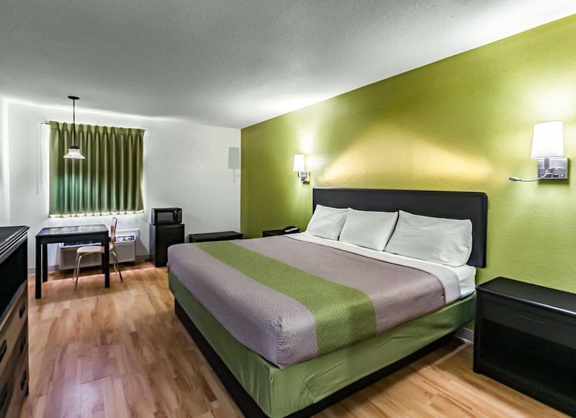 Motel 6 Augusta Ks room with king bed, desk, and green accent wall in Augusta