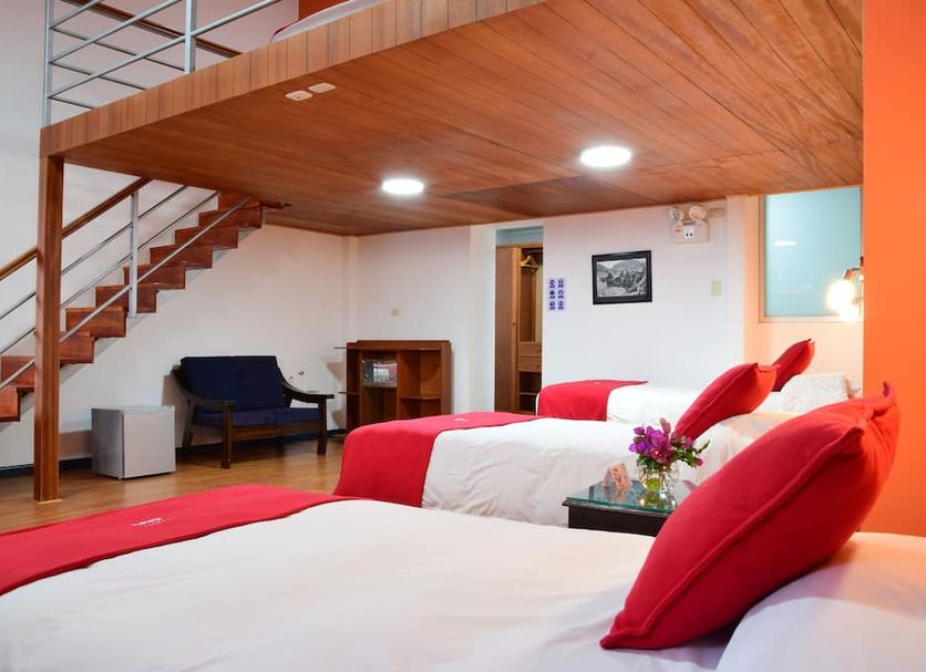 Hotel Limacpampa Cusco loft-style triple room with wooden mezzanine and red-accented beds