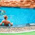 Centara Pattaya Hotel in Pattaya: guest relaxing in a turquoise outdoor pool with rock waterfall backdrop