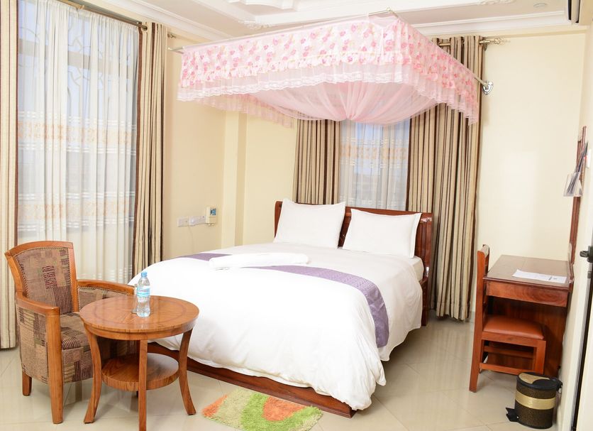 Silver Paradise Hotel, Dar Es Salaam: bed with pink mosquito net, chair, table and desk in guest room