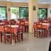 Brati - Arcoudi Hotel dining room in Arkoudi with tables, chairs, and large windows overlooking greenery