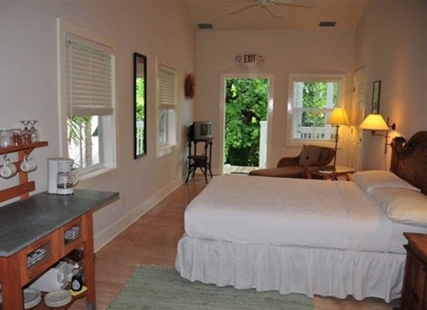Casa 325 Key West guest room with bed, windows, and a view to the green outdoor area