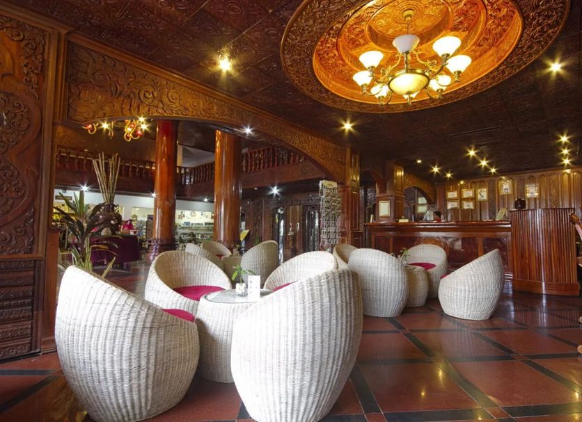 Majestic Oriental Hotel Siem Reap lobby lounge with woven white chairs and ornate carved wood ceiling