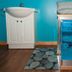 Gîte Au Coin De La Berge in Perce: fish tank beside a white cabinet and patterned bench in a colorful room