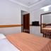 Hotel City Tower Coimbatore guest room with bed, mirror, TV, and open doorway