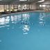 Indoor pool at Quality Inn in Perrysburg with lounge chairs and large windows