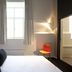 Hotel The Lodge Vilvoorde guest room with bed, window, wall art, and orange chair