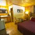 Black Bear Lodge Motel in Slade: rustic wood-paneled guest room with checkered bedspread and kitchenette