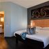 Ibis Les Herbiers guest room with double bed, bedside lamps, and abstract wall art