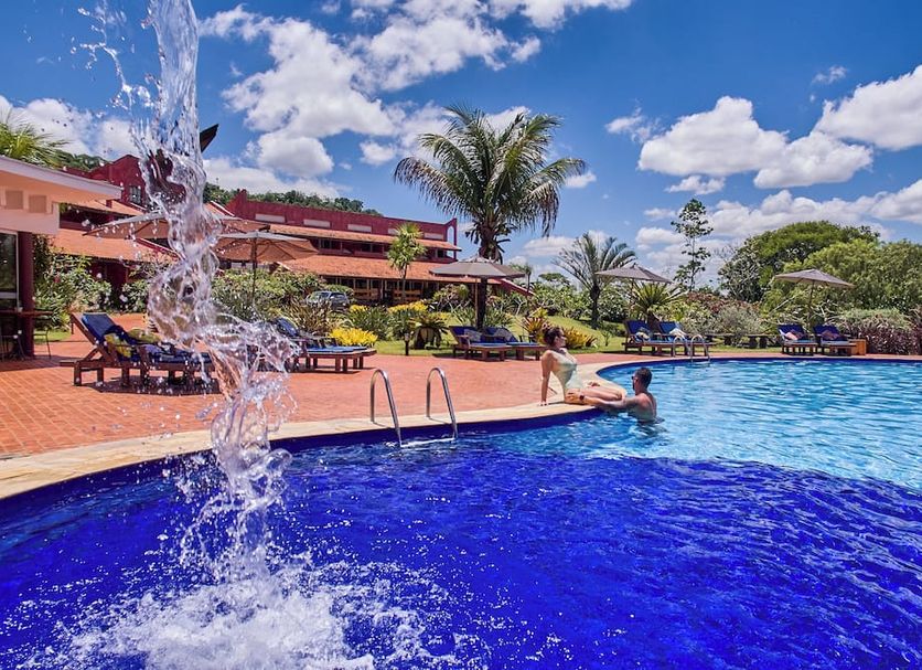 Frangipani Hotel Boutique in Brotas with outdoor pool, poolside loungers, and tropical palm trees