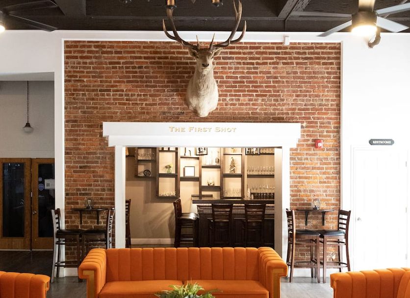 Hunter Arms Hotel in St. Cloud lobby with mounted deer head, exposed brick, bar, and orange sofa