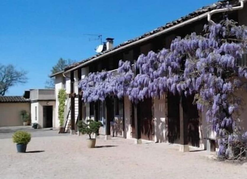 Les Barelles in Saint-Jean-de-Thurigneux with a courtyard and purple wisteria draping the facade