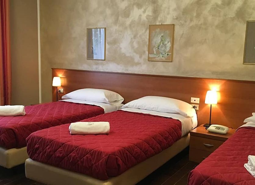 Hotel Forum in Rozzano: triple room with three single beds, red bedspreads, and bedside lamps