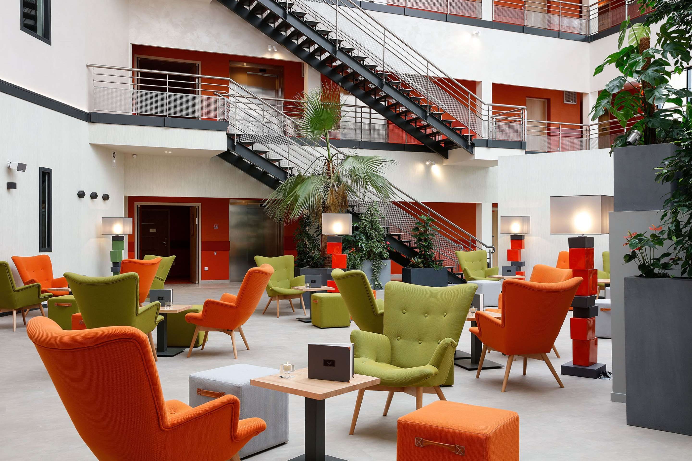 Best Western Plus Hotel Escapade Senlis lobby atrium with colorful lounge chairs and staircase in Senlis