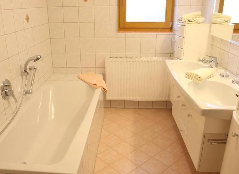 Haflingerhof in Fiss bathroom with bathtub, wall tiles, sink, radiator, and window