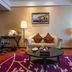 Hua Bin International Hotel Beijing sitting area with sofa, coffee table, desk, lamps and purple rug