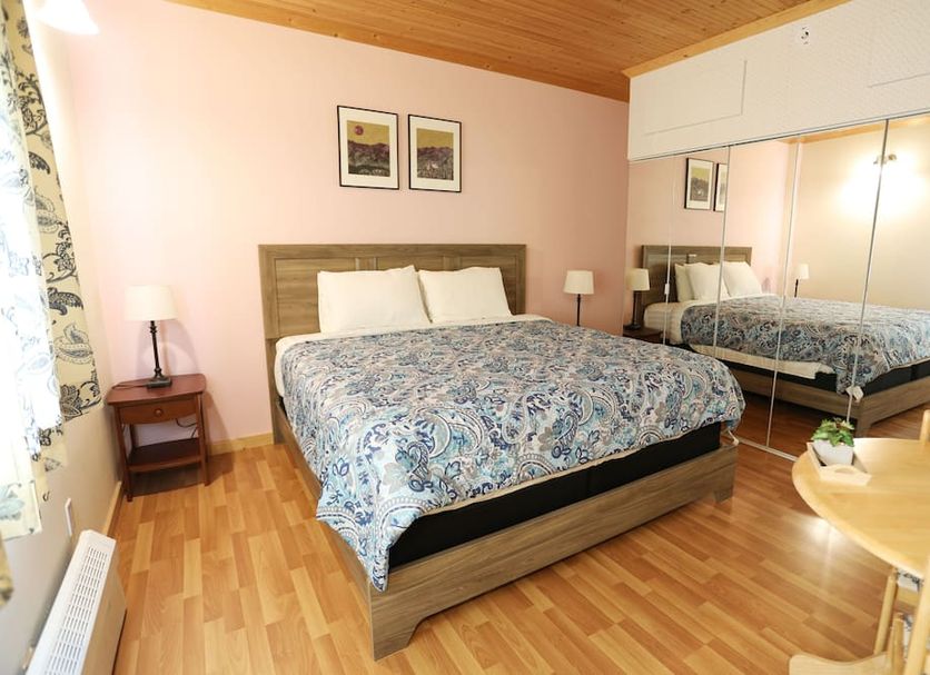 Kaleido Lodge Yukon in Whitehorse guest room with queen bed, mirrored closet and wood flooring