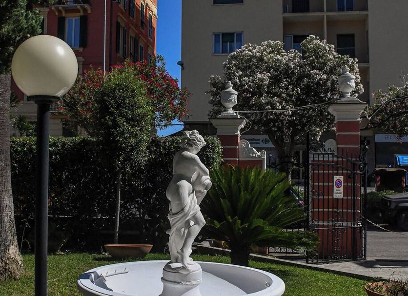 Hotel Le Palme Varazze courtyard with statue, lamp post, flowering greenery and building entrance