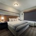 AmericInn by Wyndham Galesburg guest room with king bed, bedside lamps, and window with blackout blind